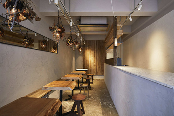 厚みのある木製のテーブルとシンプルな白壁が印象的な店内