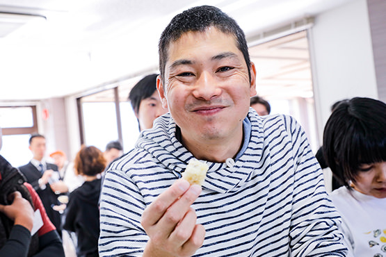 白いカキフライを実食し笑顔を見せる鈴木隆研究員